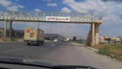 الأسد يسرق المصاري  .. يافطة معلقة في عقر دار الأسد